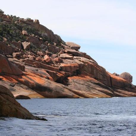 a rocky hillside next to a body of water