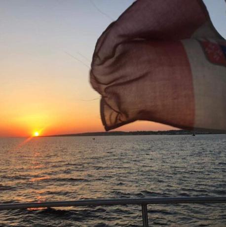 et flag på et krydstogtskib med solnedgangen i baggrunden