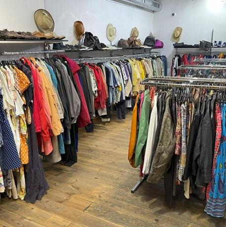 a bunch of clothes on racks in a store