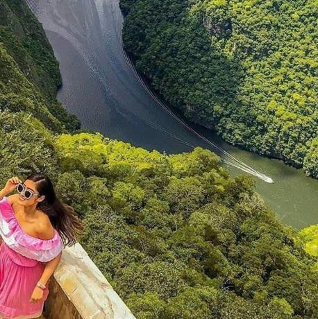 Una mujer parada en una cornisa mirando un río
