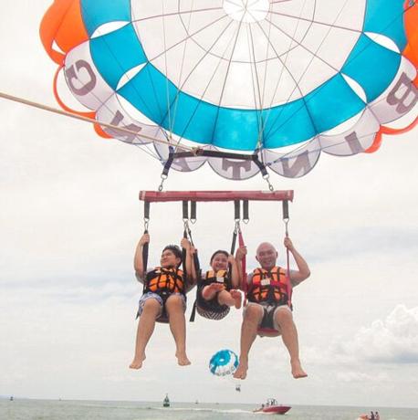 two people are hanging from a parachute on the beach