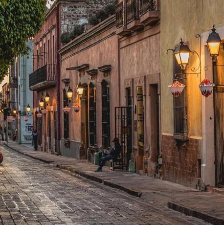 a person sitting on a bench on a cobblestone street
