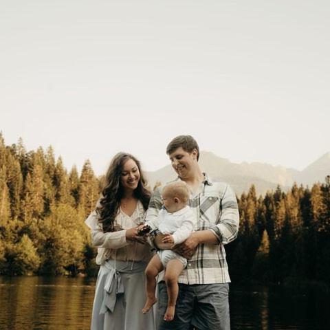 ein Mann und eine Frau halten ein Baby vor einem See