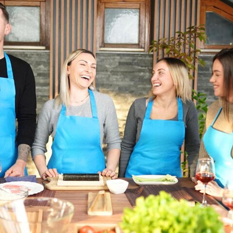 a group of people wearing aprons standing around a table