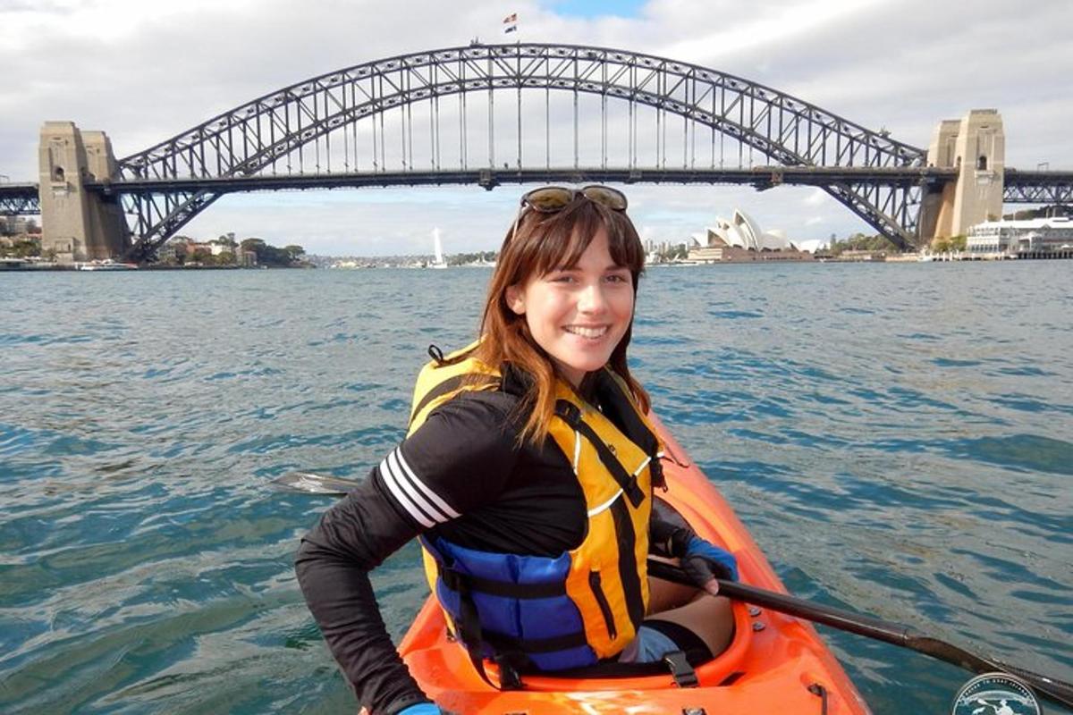 eine Frau in einem Kajak im Wasser vor einer Brücke