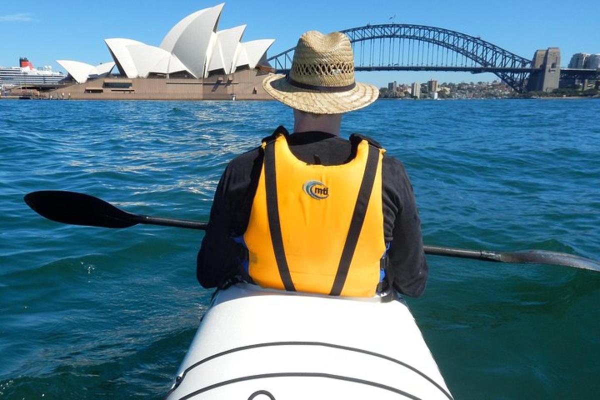 ein Mann in einem Kajak im Wasser mit dem Sydney Opera House