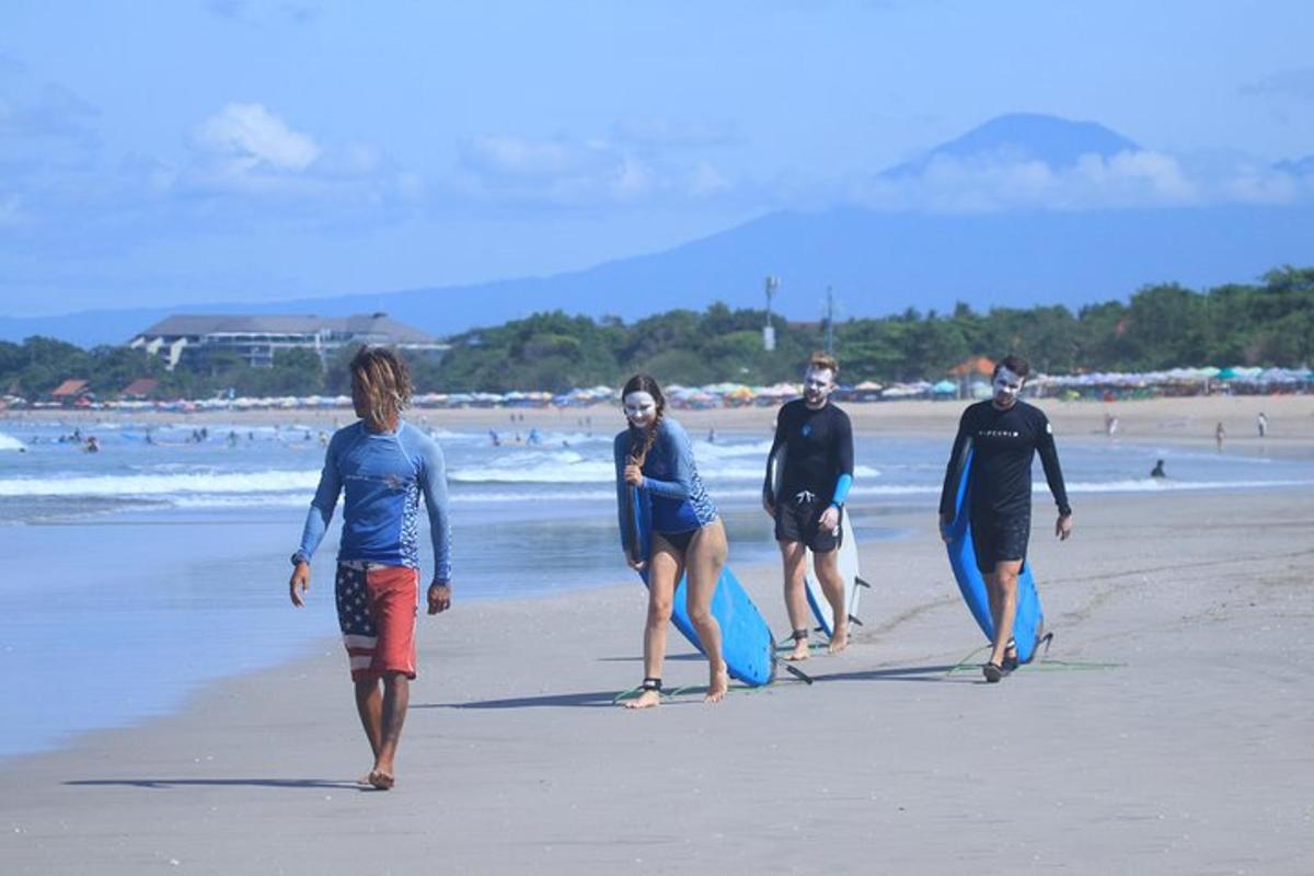 a group of people walking on the beach with surfboards