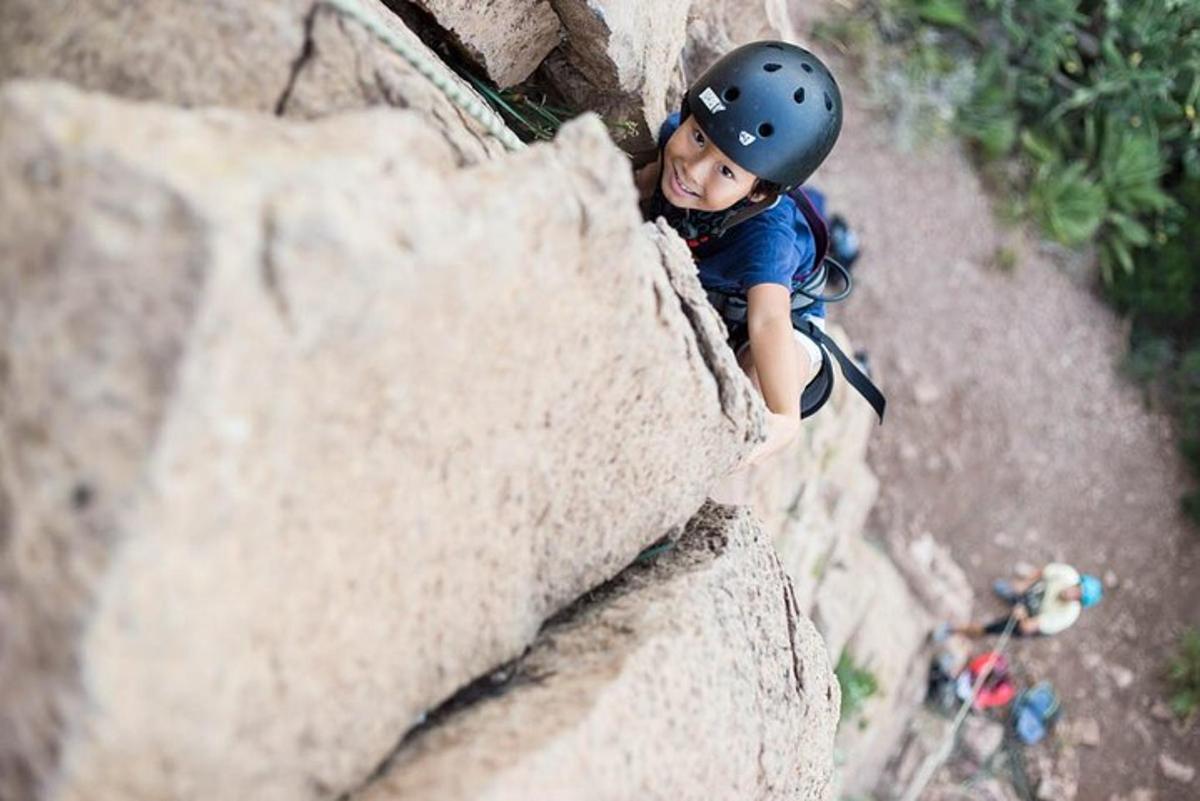 una ragazza con il casco che scala una parete rocciosa