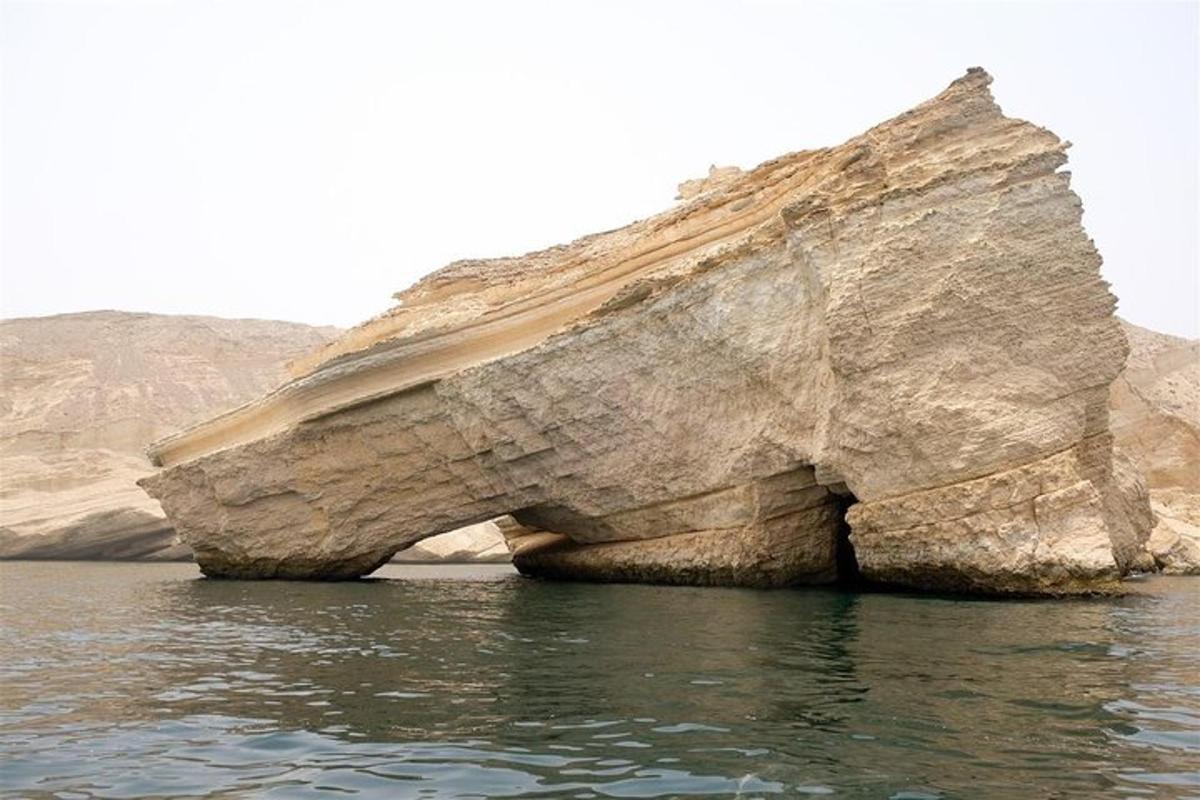 a large rock in the water near the ocean