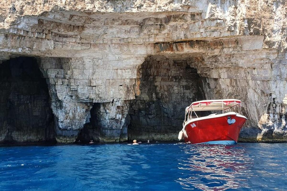 una barca rossa nell'acqua accanto a una grotta