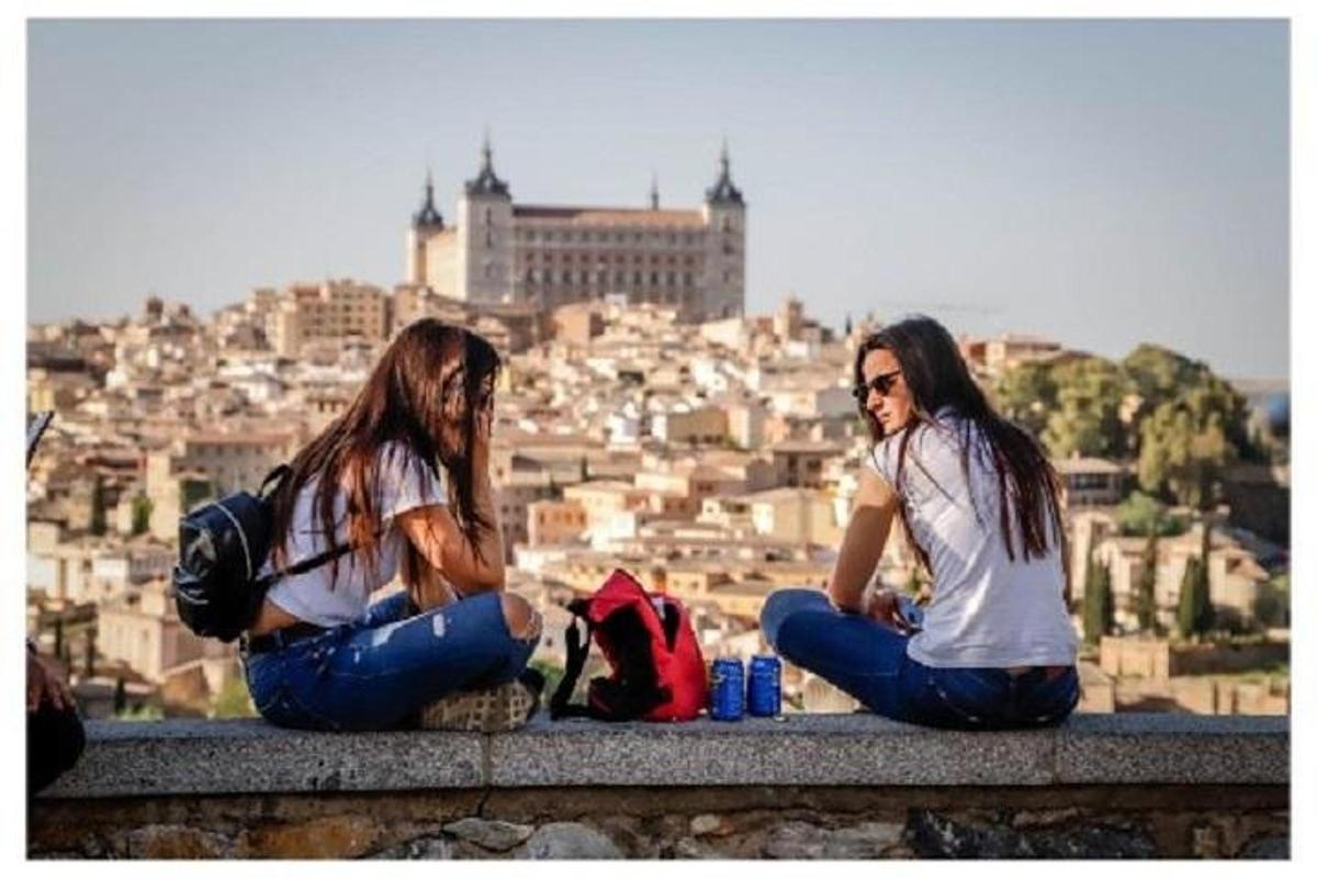 due donne sedute su una sporgenza che guardano una città