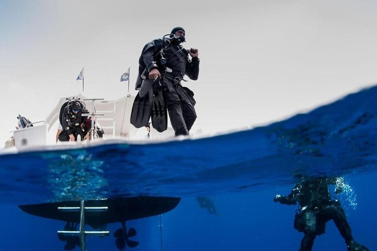 a man standing on the back of a boat in the water