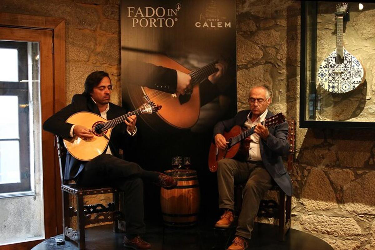 dois homens estão sentados em cadeiras tocando violão