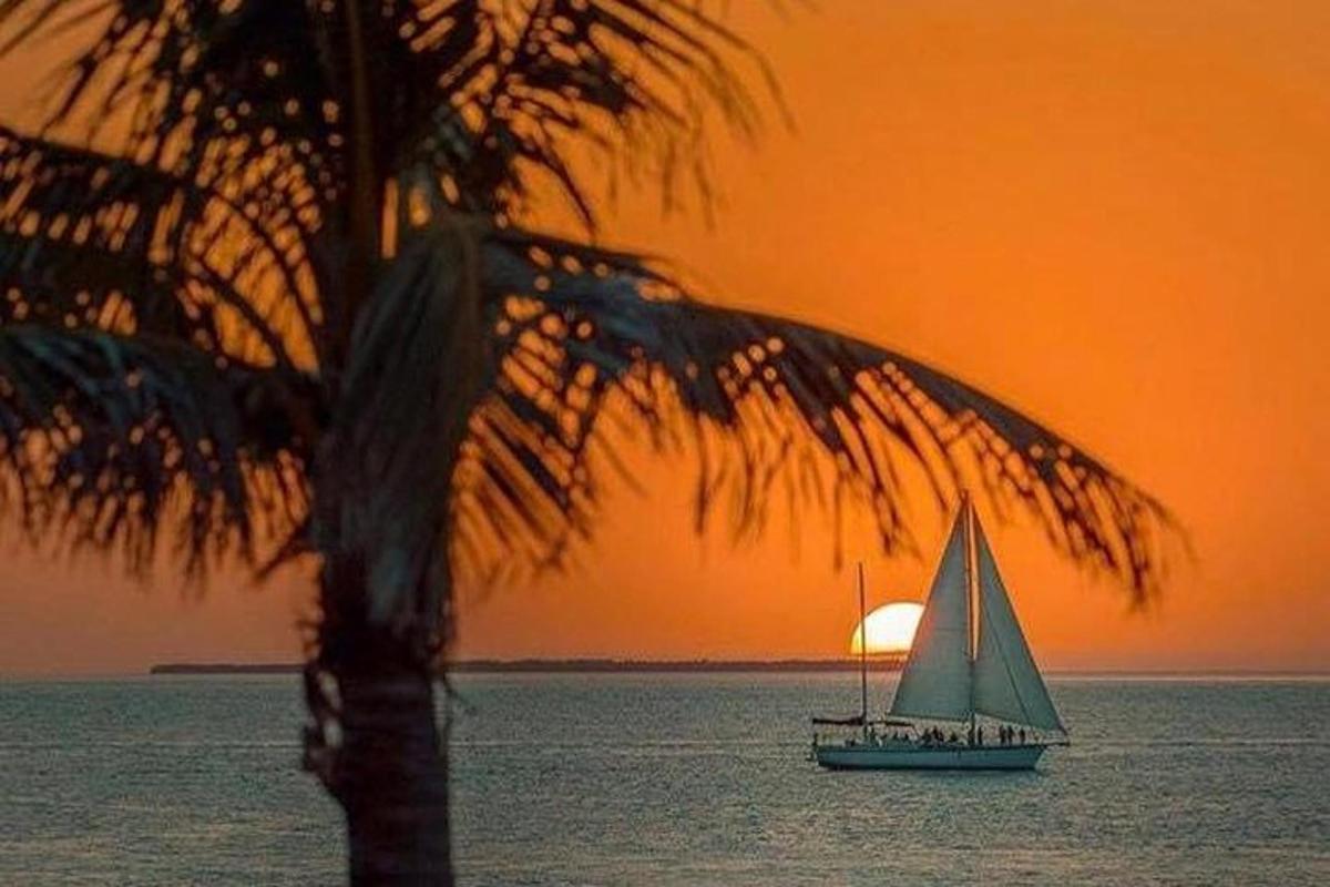 a sailboat in the ocean with a sunset in the background
