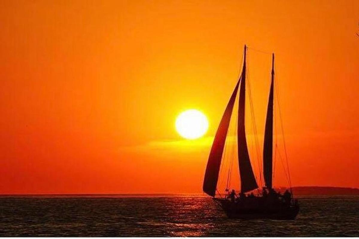 a sail boat in the ocean at sunset