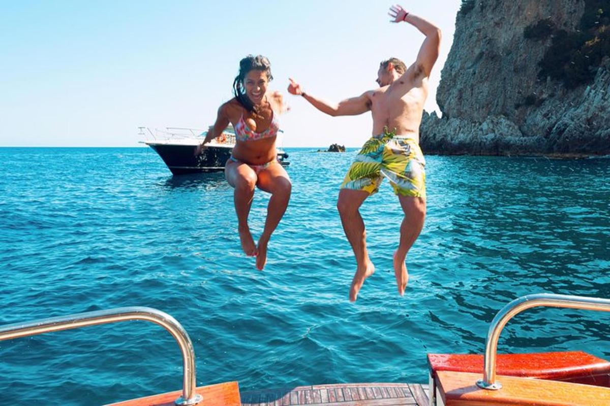 ein Mann und eine Frau springen von einem Boot ins Wasser