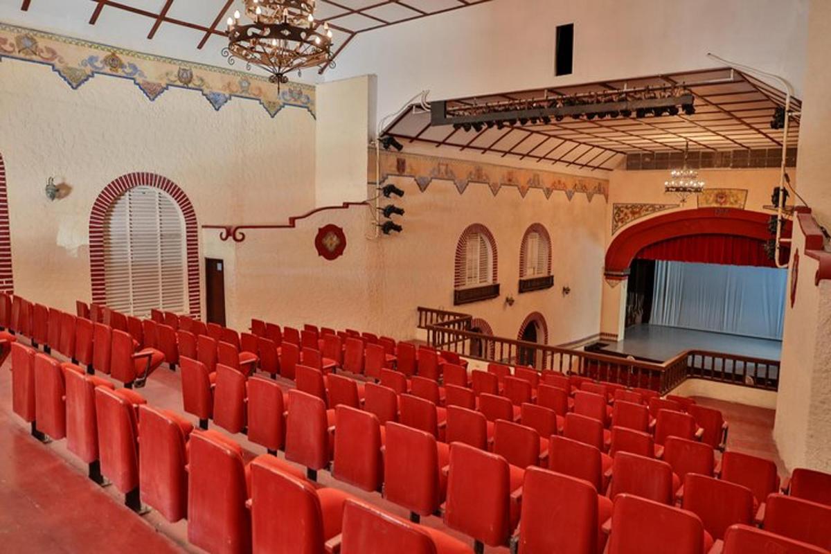 an auditorium with red chairs and a stage