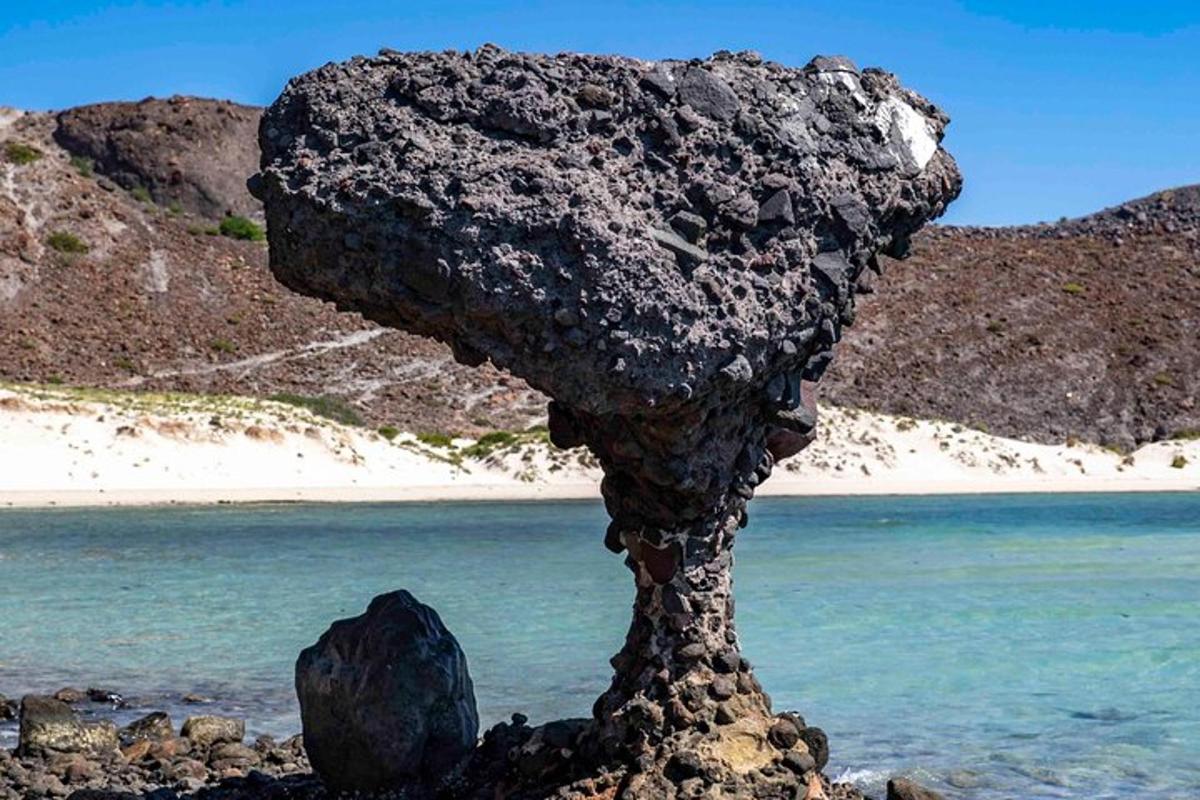 batu yang duduk di atas pantai di sebelah air
