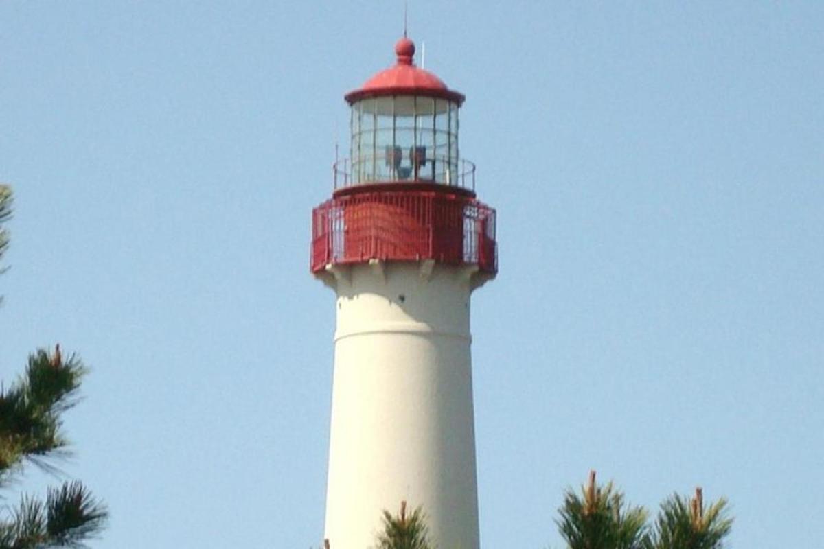 a red and white lighthouse with a palm tree
