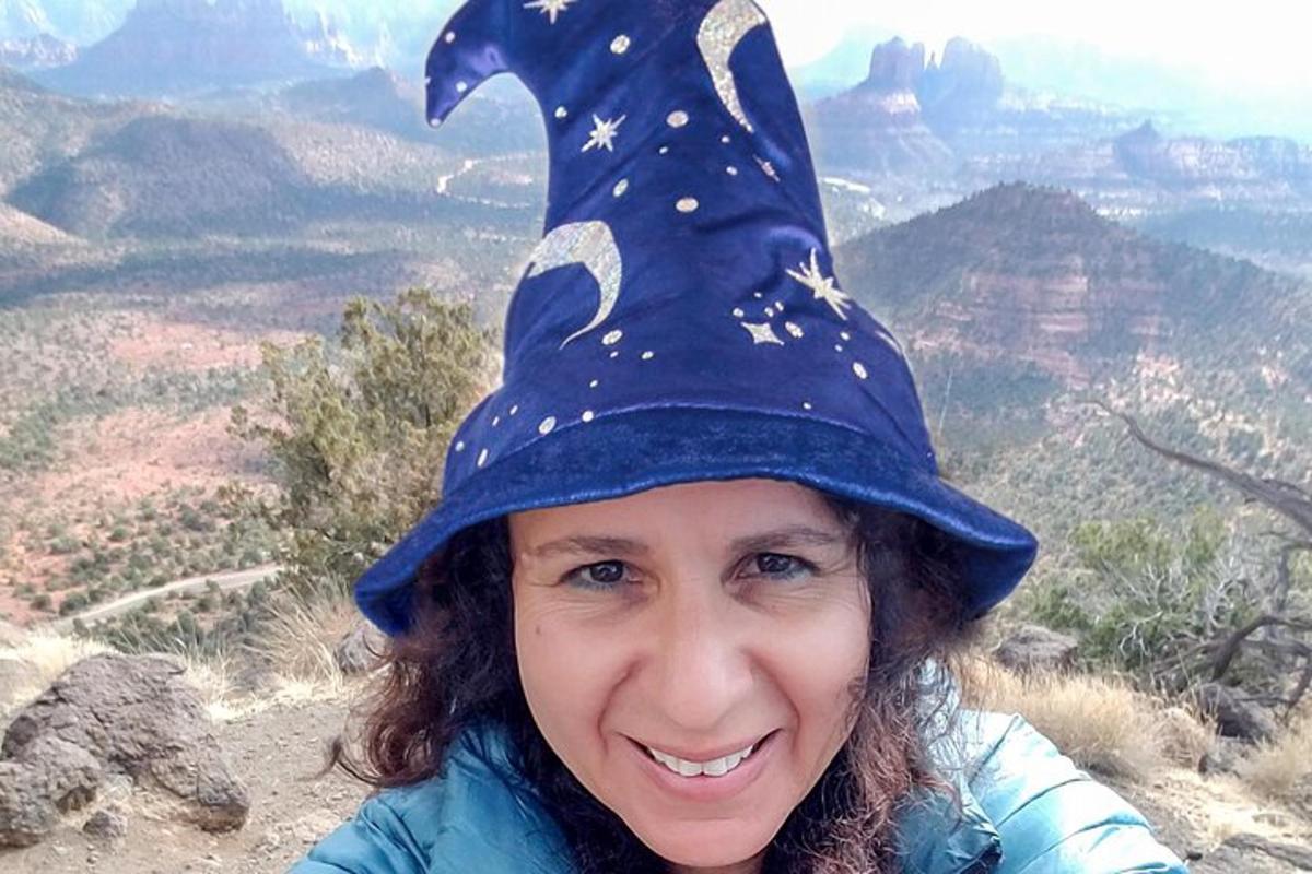 a girl wearing a witch hat on top of the grand canyon