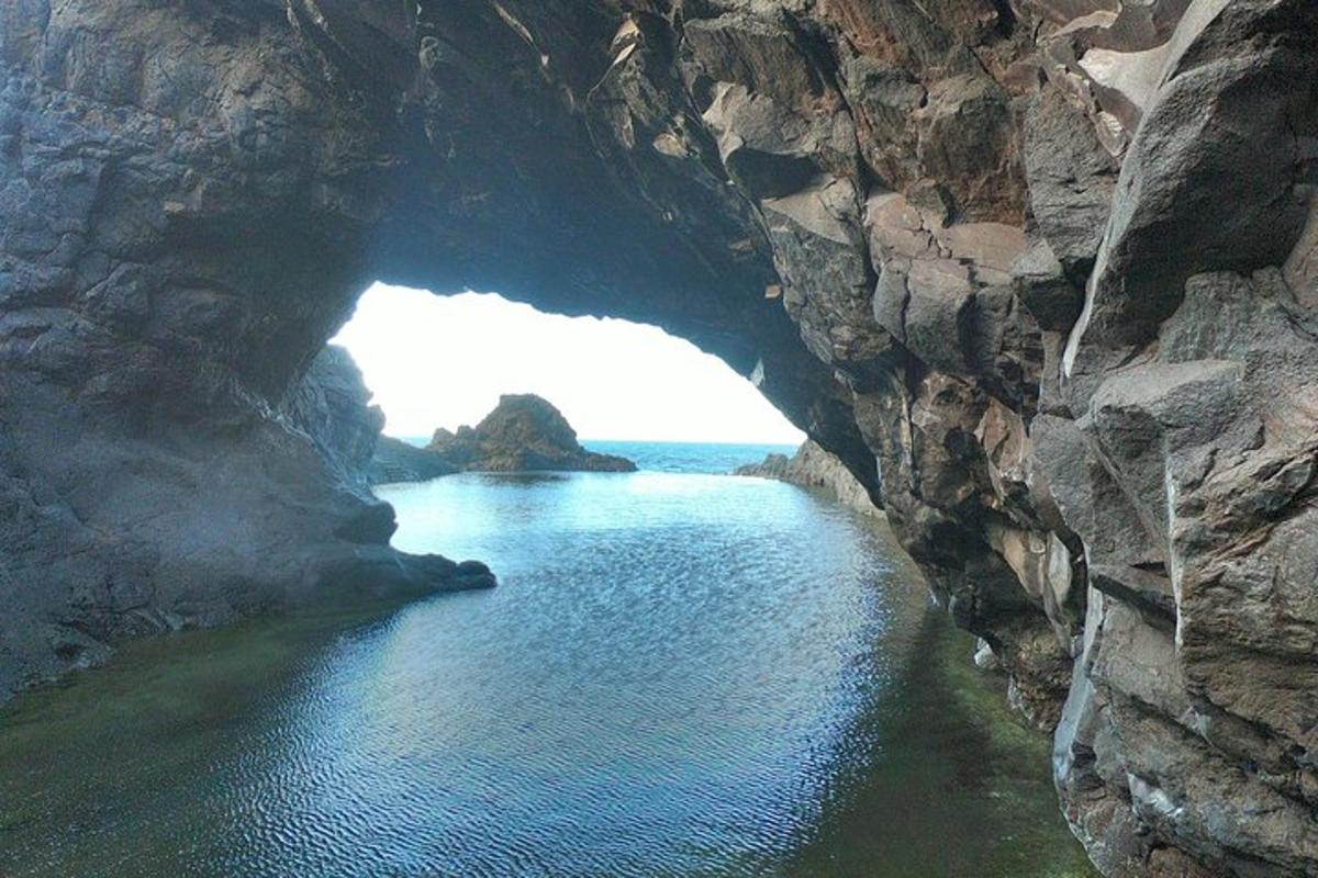una cova en una muntanya rocosa amb l'oceà