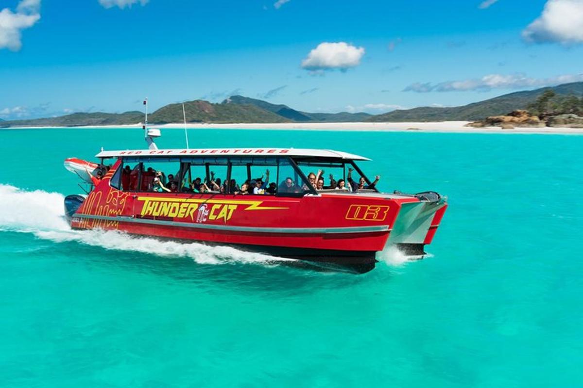a red boat in the water with people on it