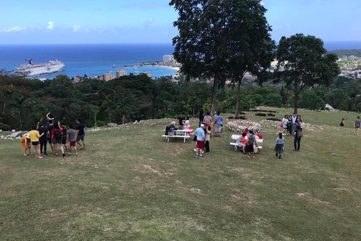 eine Gruppe von Menschen steht um einen Picknicktisch auf einem Hügel