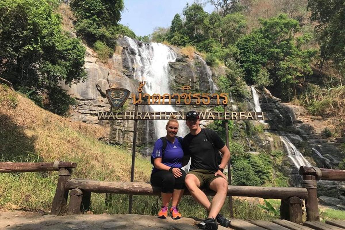 un uomo e una donna seduti su una panchina davanti a una cascata