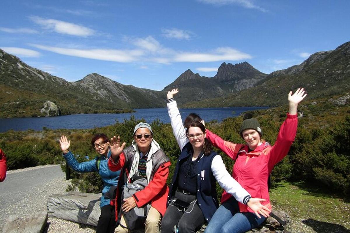 a group of people sitting on a rock with their hands in the air