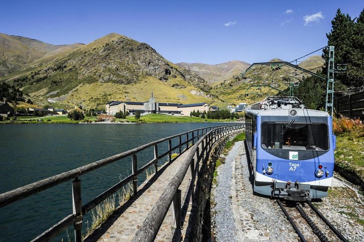 a blue train on tracks next to a body of water