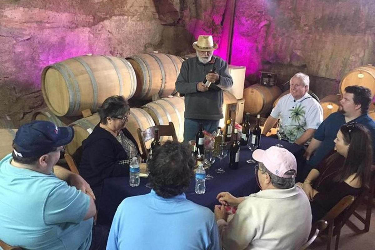 a group of people sitting around a table in a wine cellar
