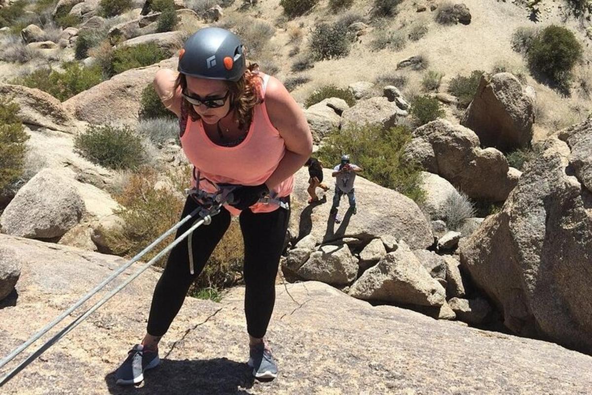 una donna con una maglietta rosa in piedi su alcune rocce