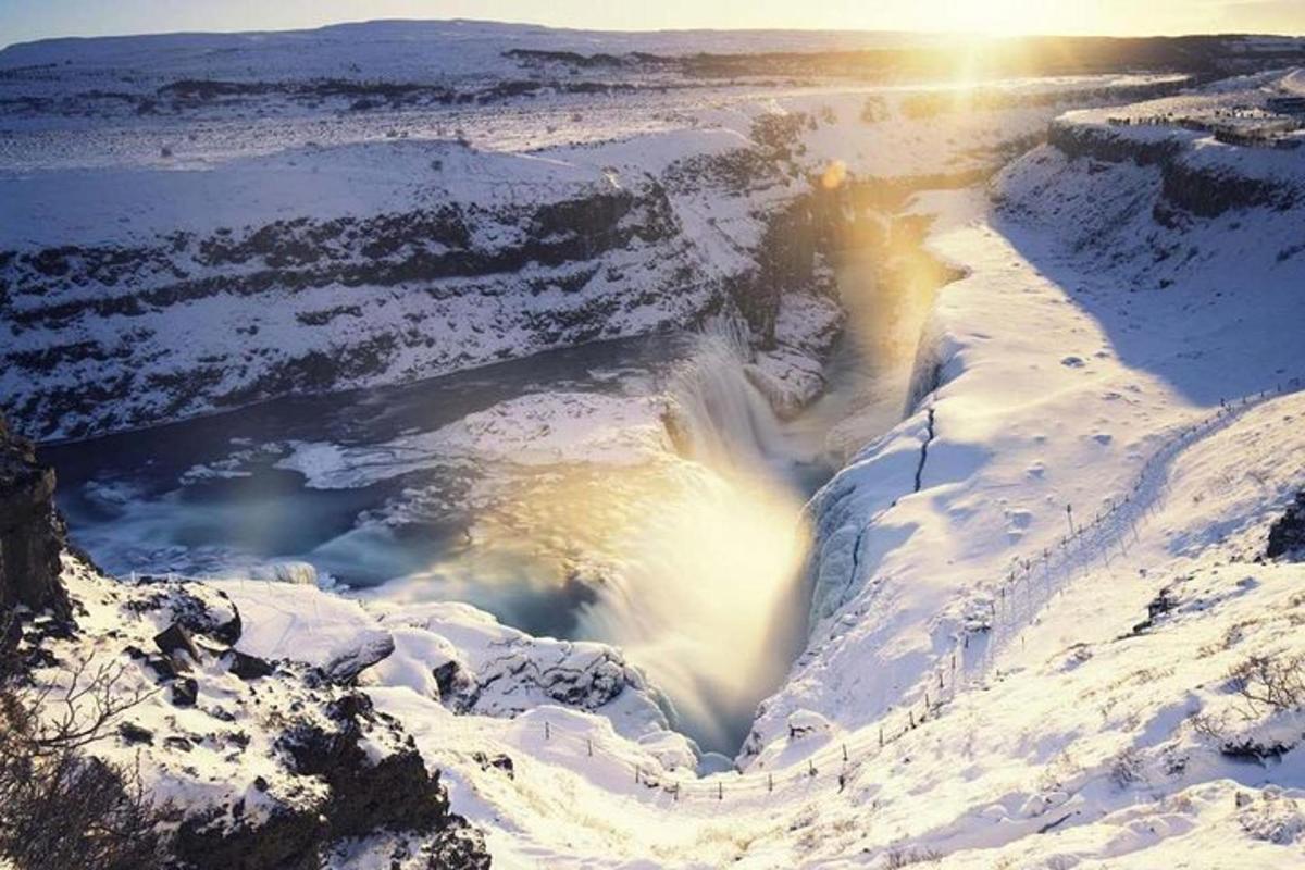 Una cascada en la nieve con el sol al fondo.