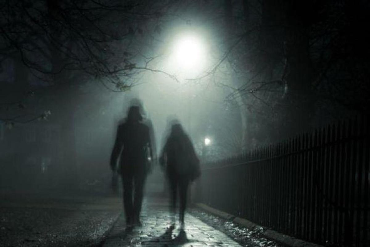 two people walking down a street at night