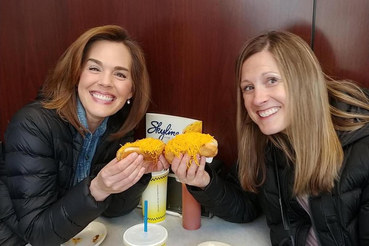 two women sitting at a table with two hot dogs