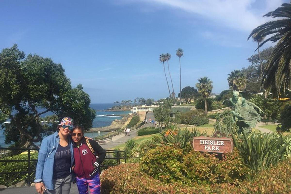 two people posing for a picture in front of a park