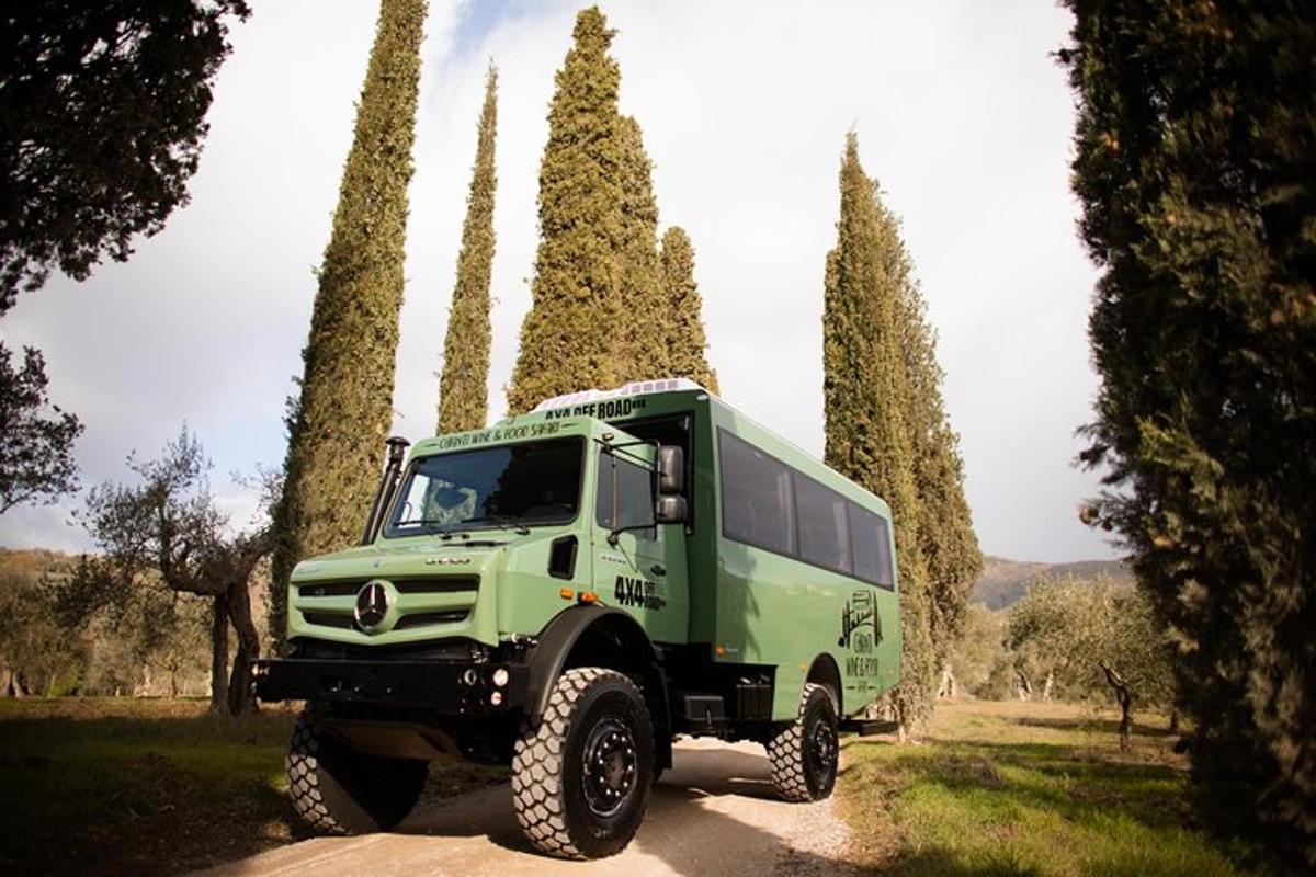 un camion verde parcheggiato su una strada sterrata con alberi