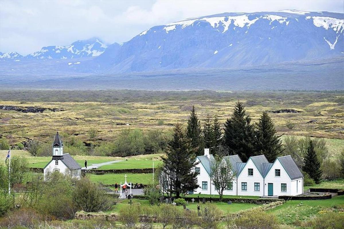 una casa bianca in un campo con le montagne sullo sfondo