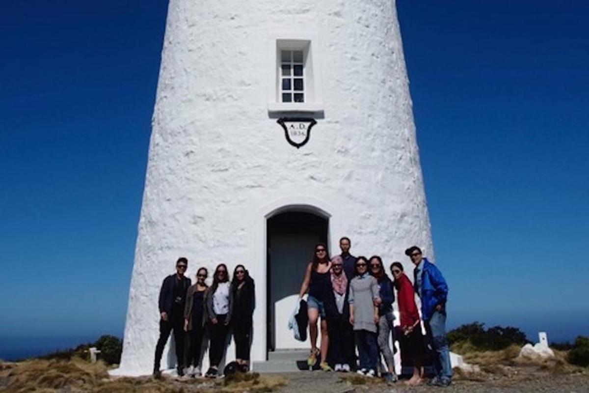 um grupo de pessoas em pé em frente a um farol