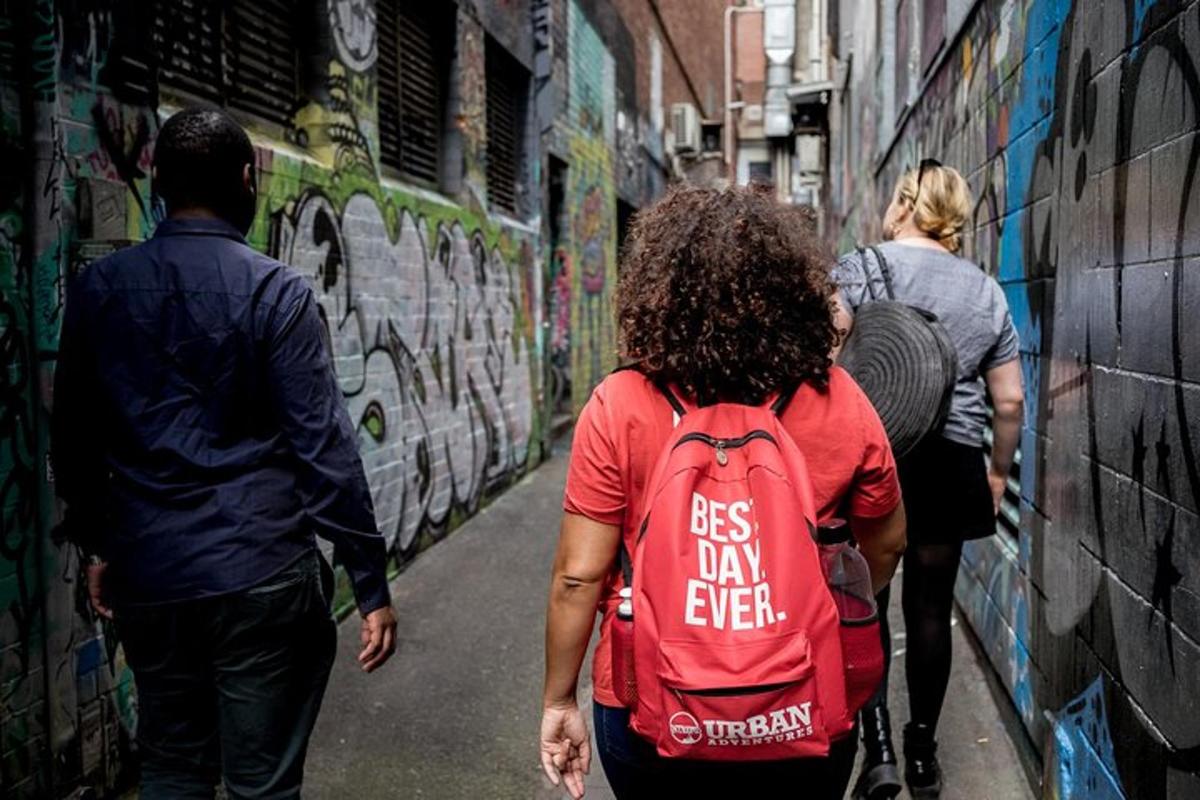 a group of people walking down a alley with graffiti