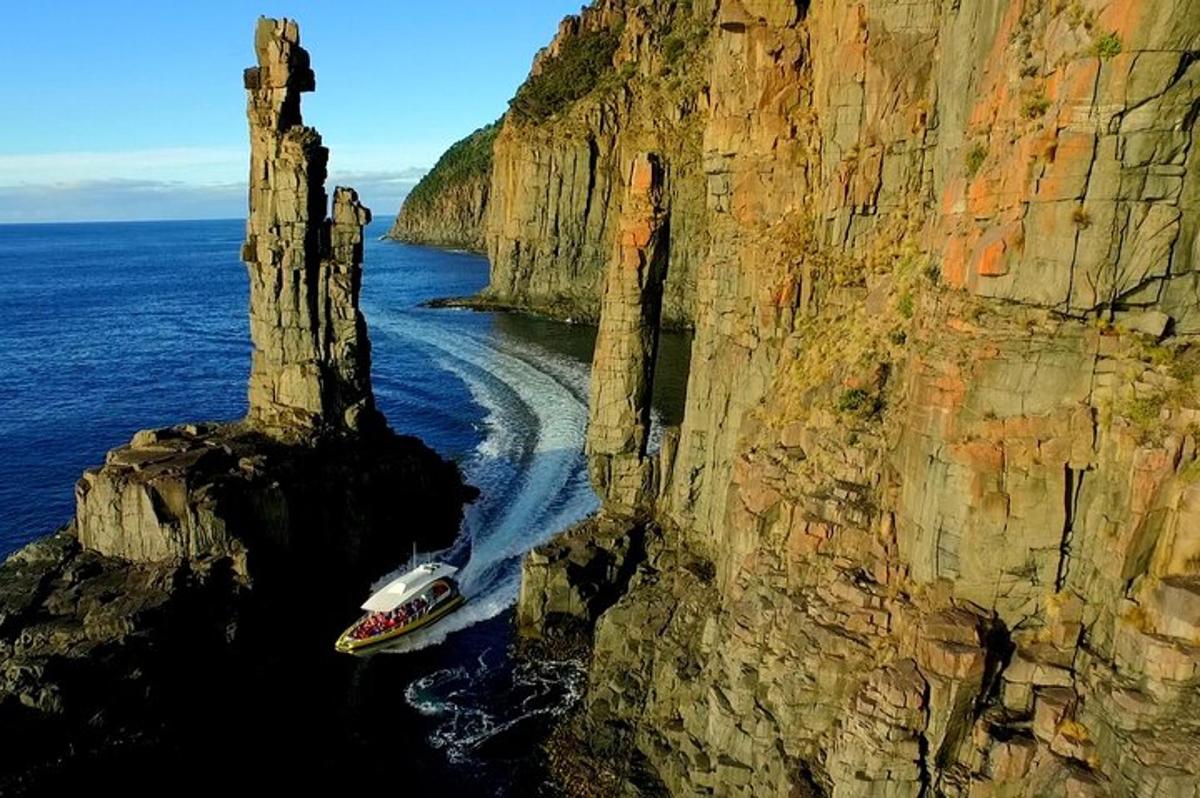 a boat in the water next to a cliff