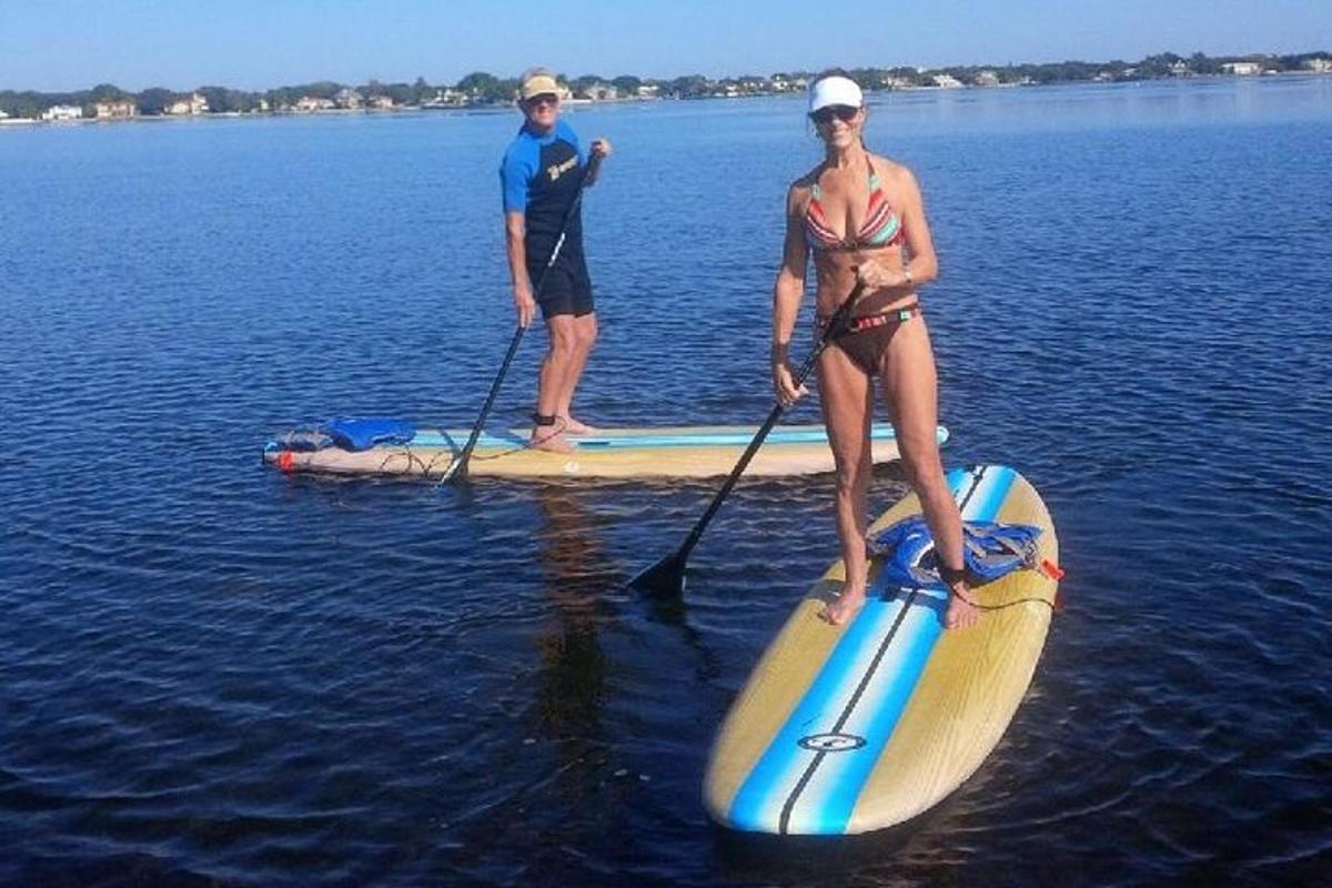 un bărbat și o femeie pe o placă de paddle în apă