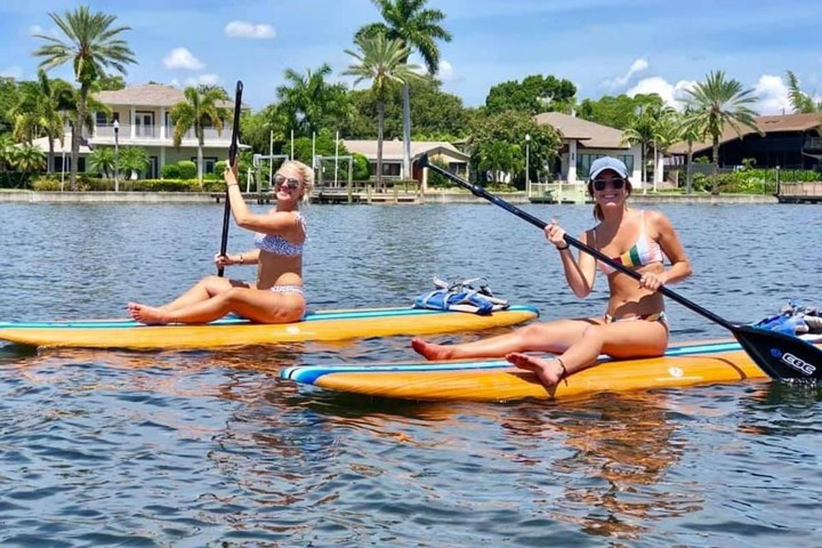 due donne in costume da bagno sedute sui kayak sull'acqua