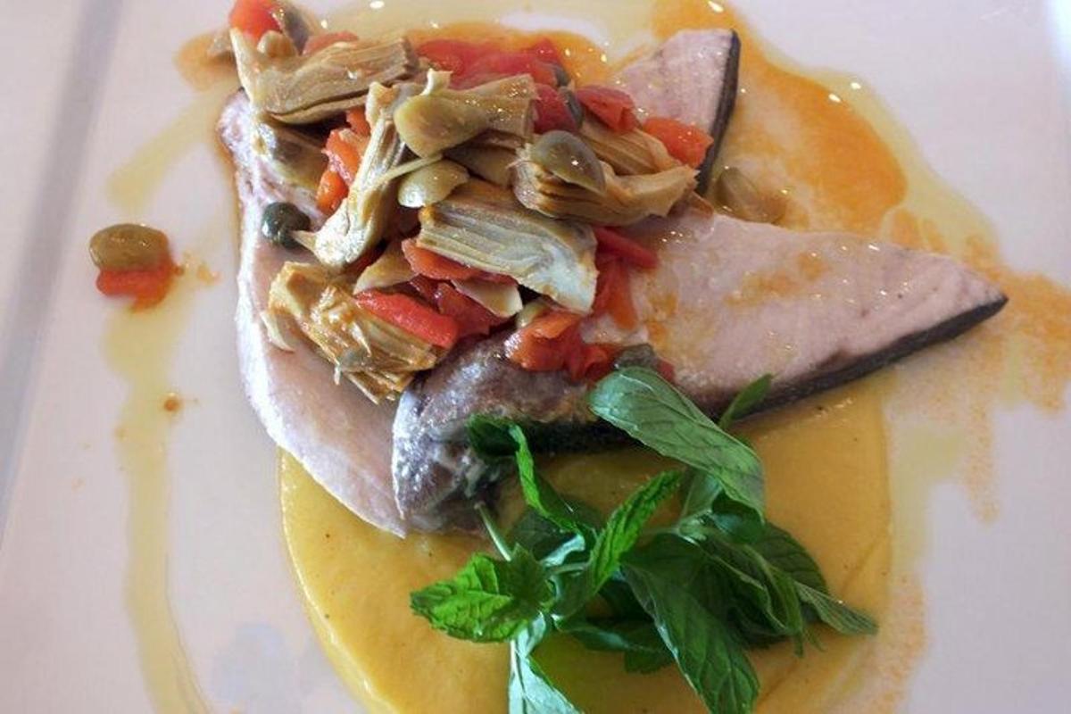 Un plato de comida con carne y verduras encima.