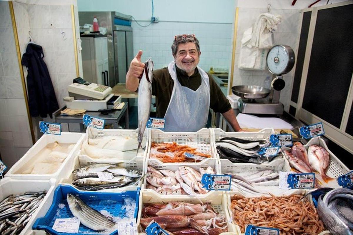 Un hombre parado frente a una mesa de pescado