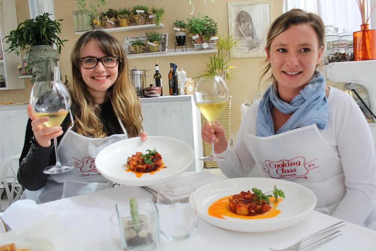 Dos mujeres sentadas en una mesa con platos de comida y vino.