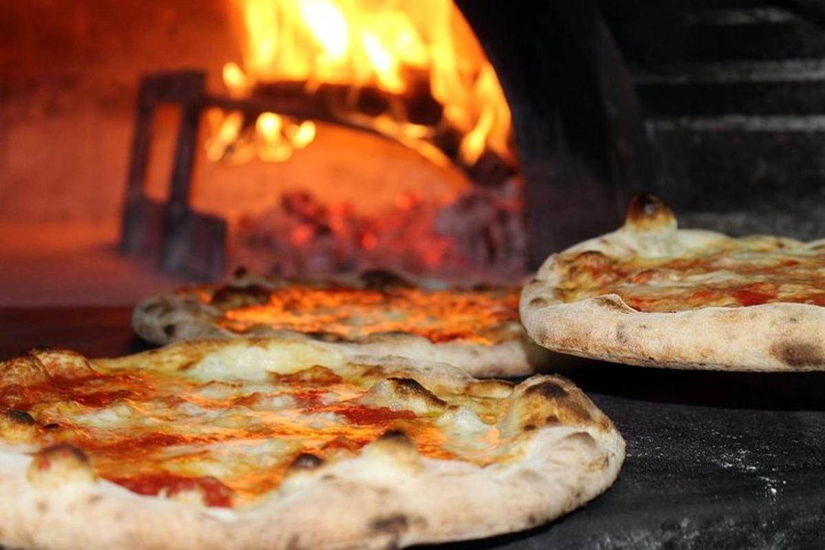 three pizzas in front of a fire oven