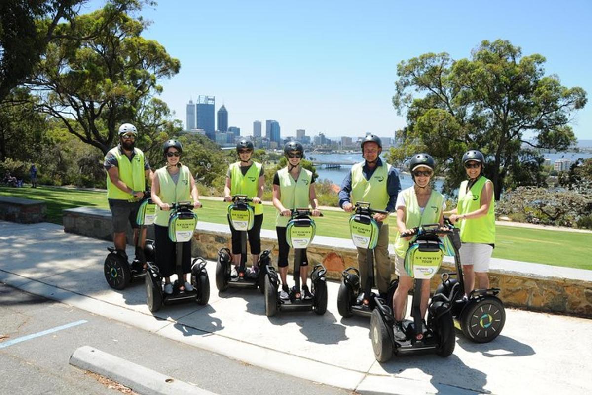 a group of people in green shirts riding on segways