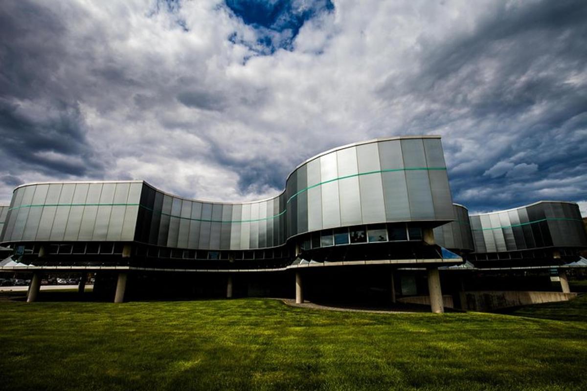 a large glass building with a field in front of it