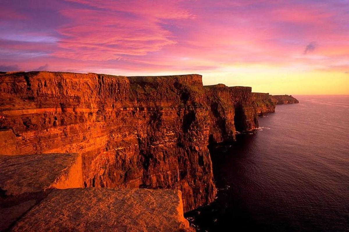 una scogliera con il sole che tramonta sull'oceano